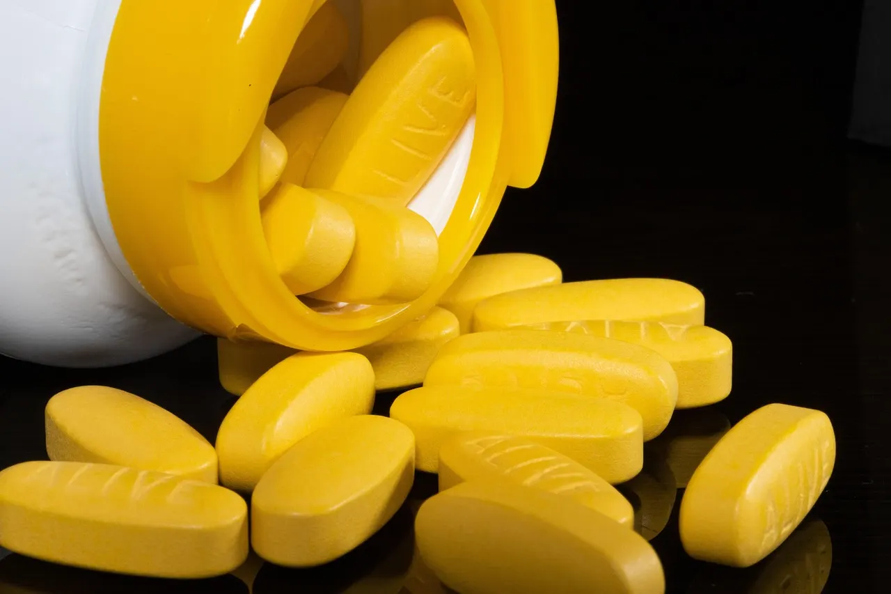 Close up of white statin pills spilling from an amber prescription bottle on a table
