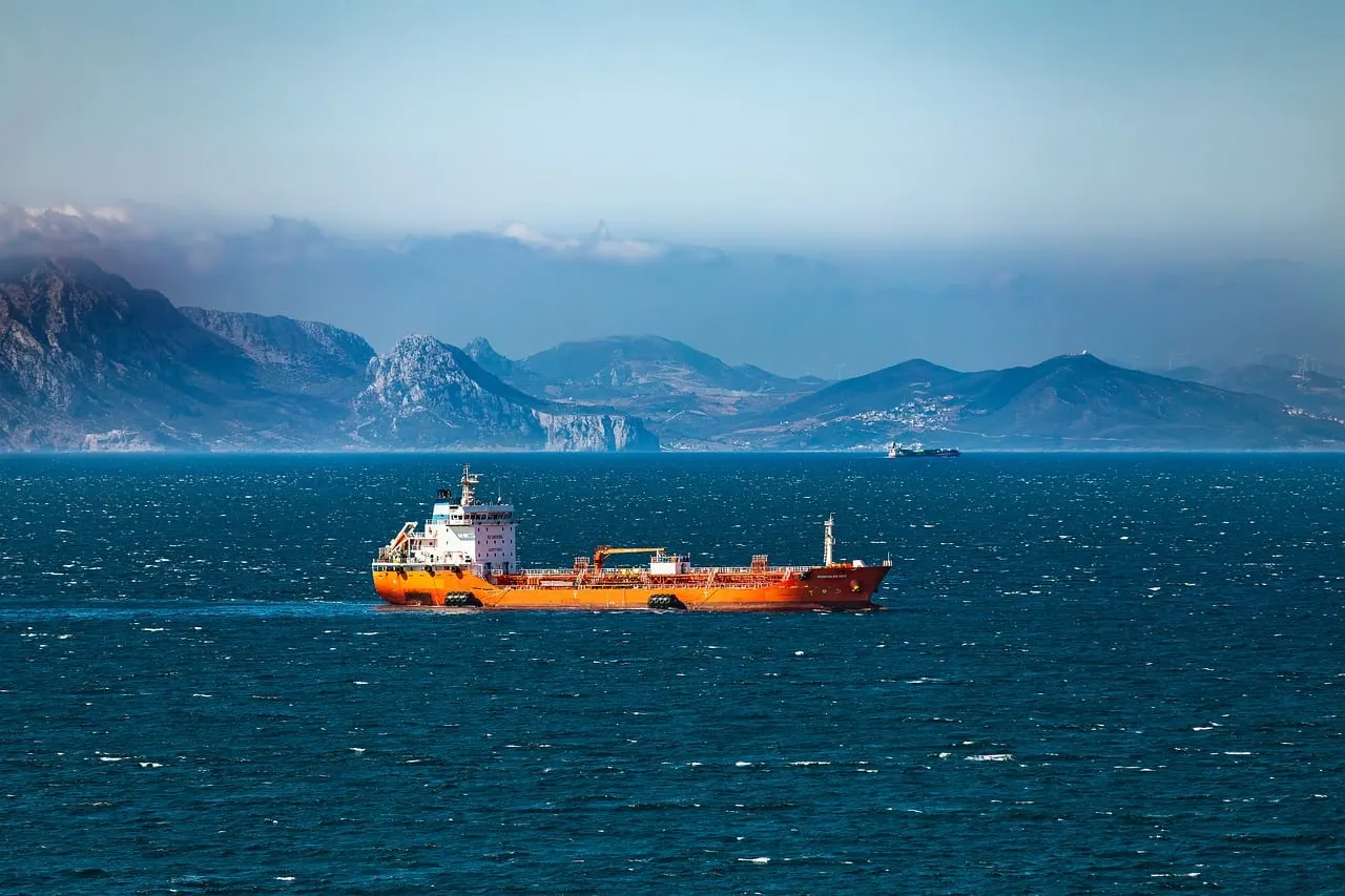 An oil tanker transits the Strait of Hormuz under a cloudy sky.