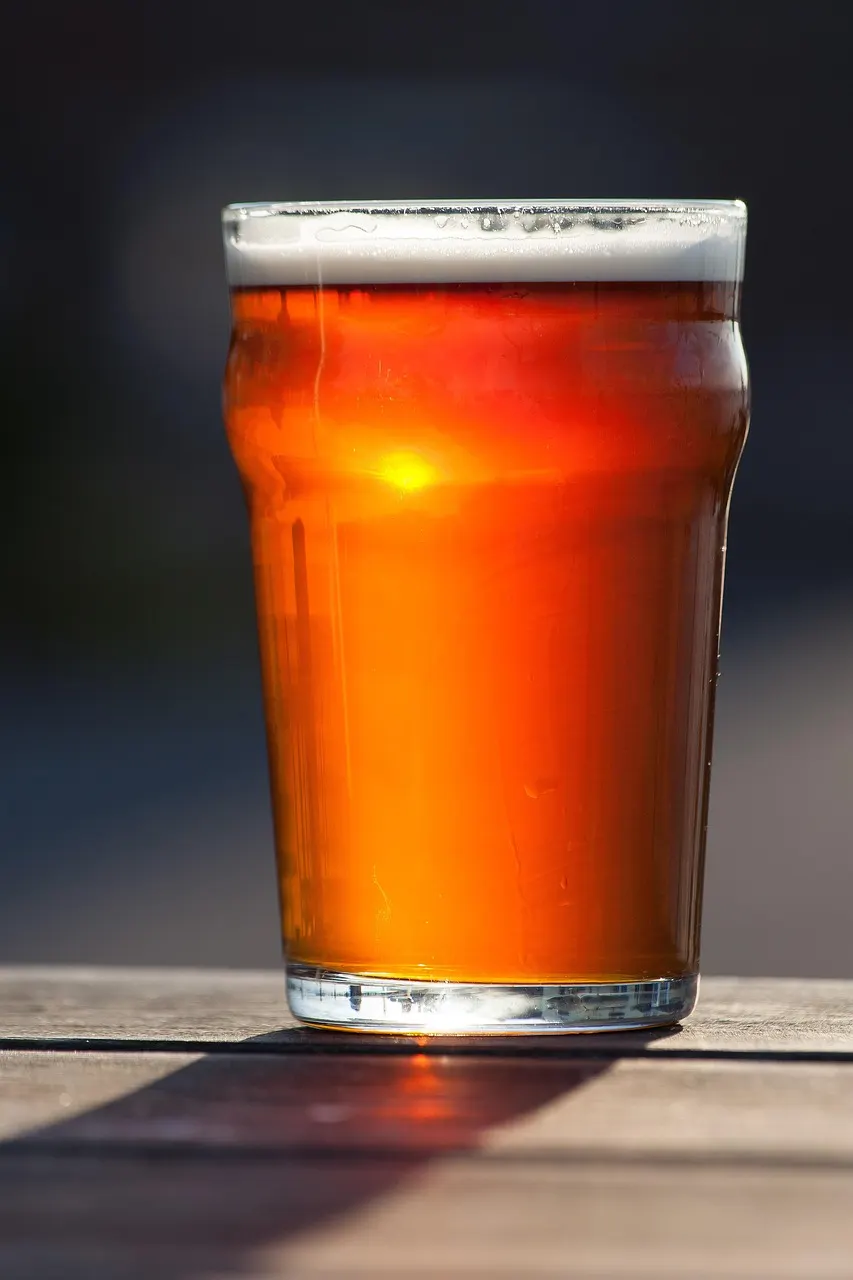 pessoa segurando haltere e copo de cerveja representando álcool e musculação