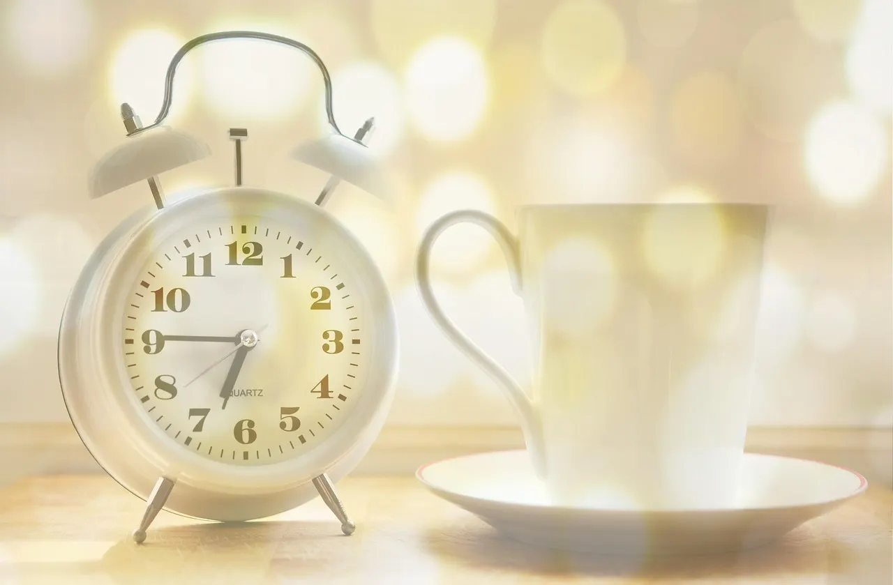 Person sitting up in bed looking at an alarm clock in the dark