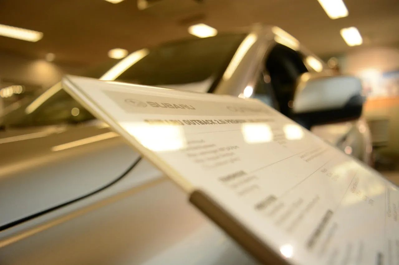 New cars parked at dealership with price signs