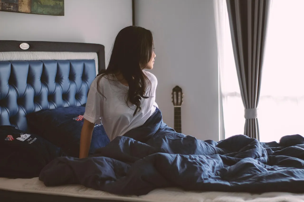 Cama em quarto escuro e silencioso com luz suave pela janela