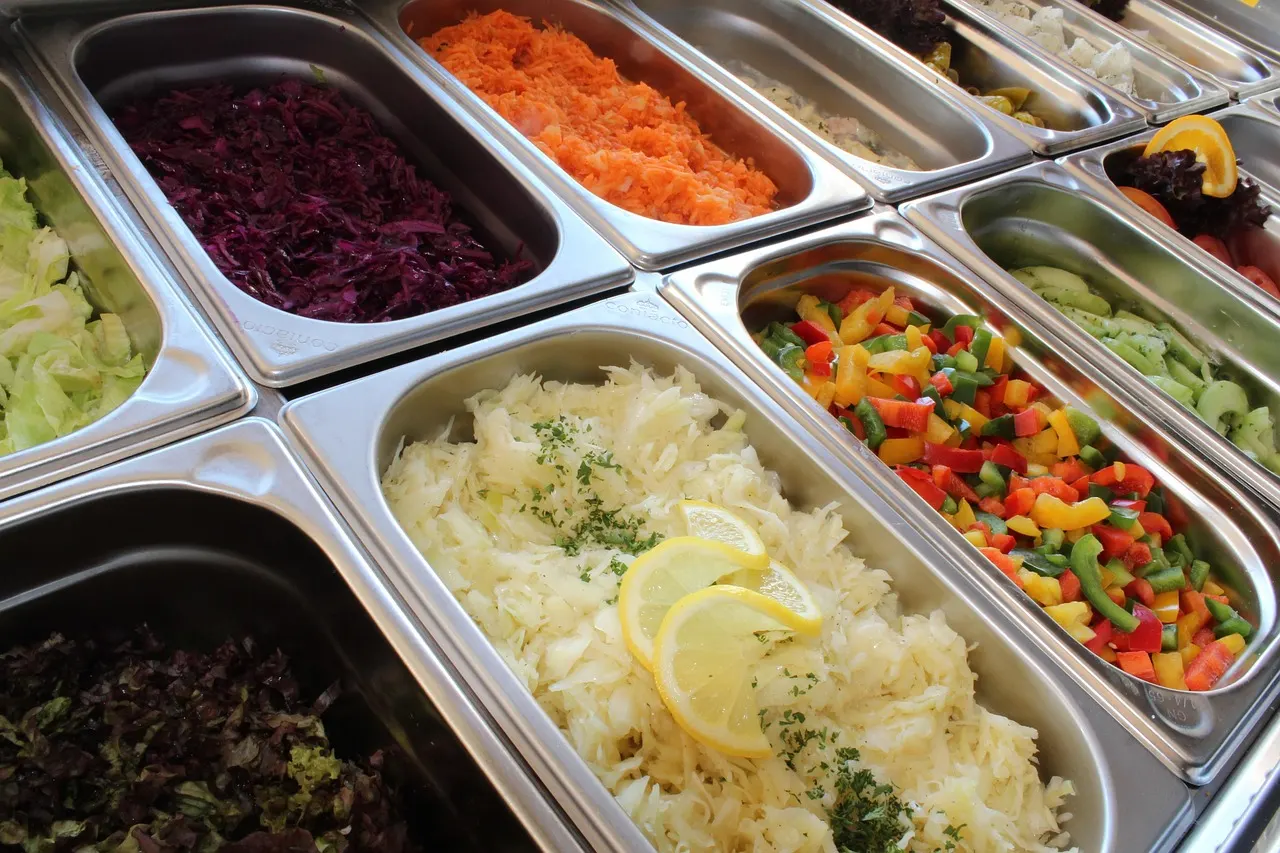 Pessoa montando um prato saudável no self service começando pela salada