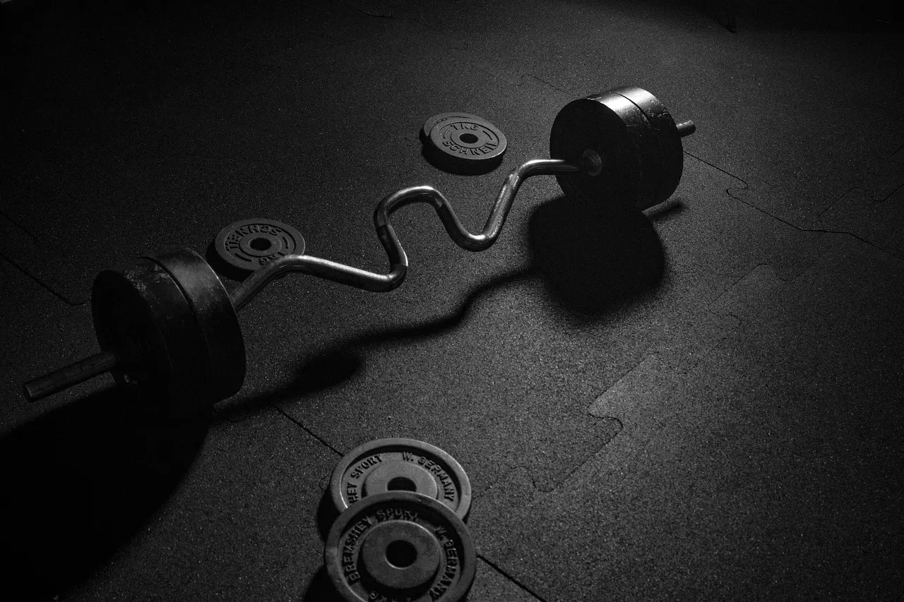 Barra com anilhas e cronômetro na academia — intervalo entre séries na musculação
