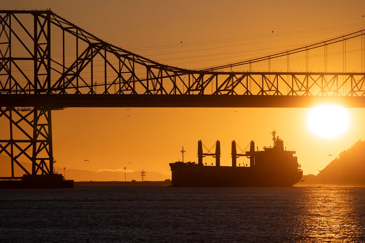 An oil tanker navigating turbulent waters near a coastal refinery