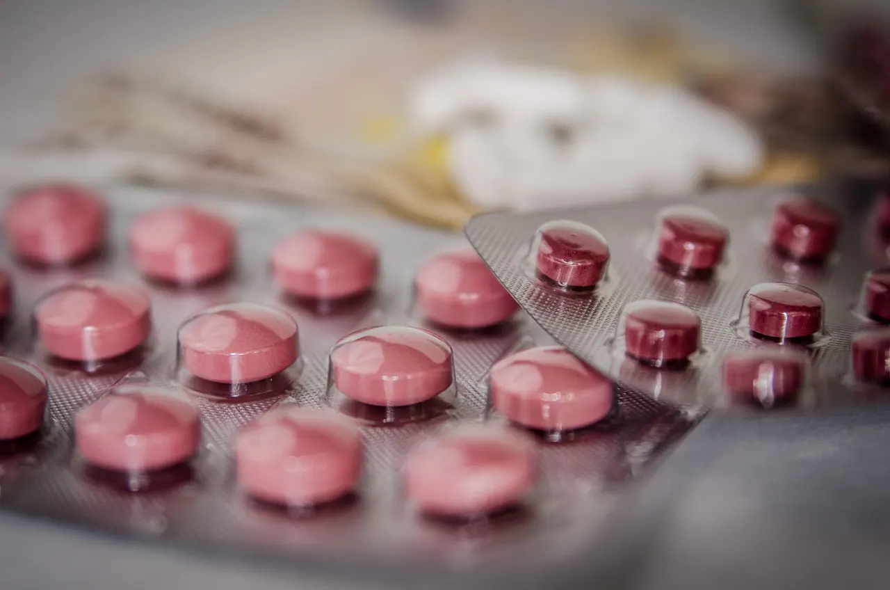 Close-up of hands organizing a weekly pill dispenser with pain medication.