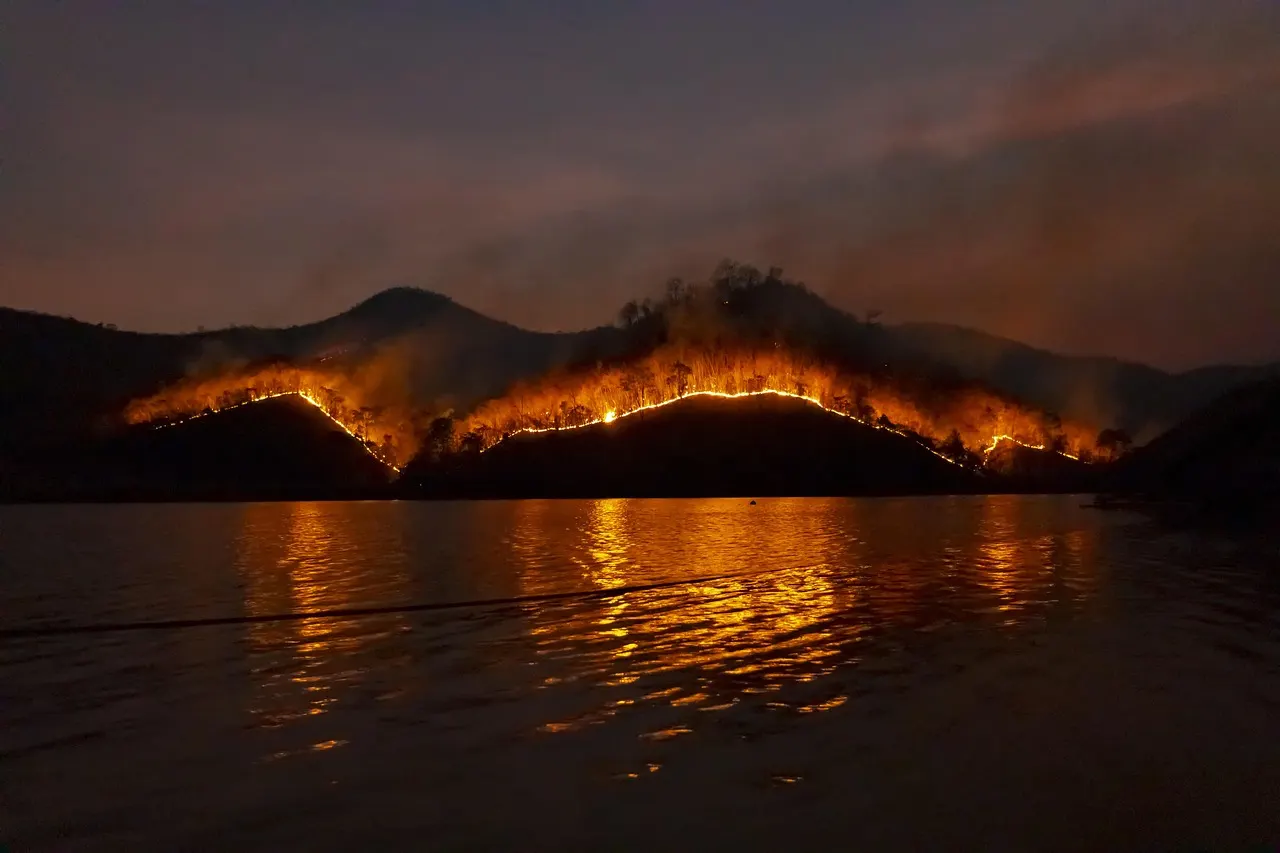 Thick black and gray smoke billows from a wildfire threatening a residential area